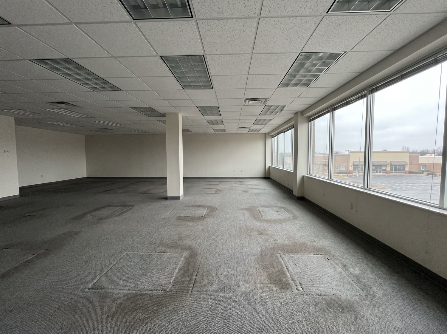 An emptied open-plan office suite with bare carpet tiles showing where desks stood