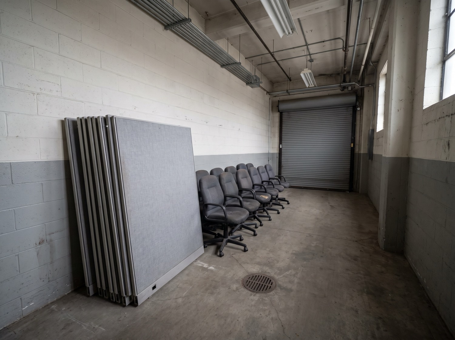 Cubicle panels stacked and office chairs staged near a loading dock door
