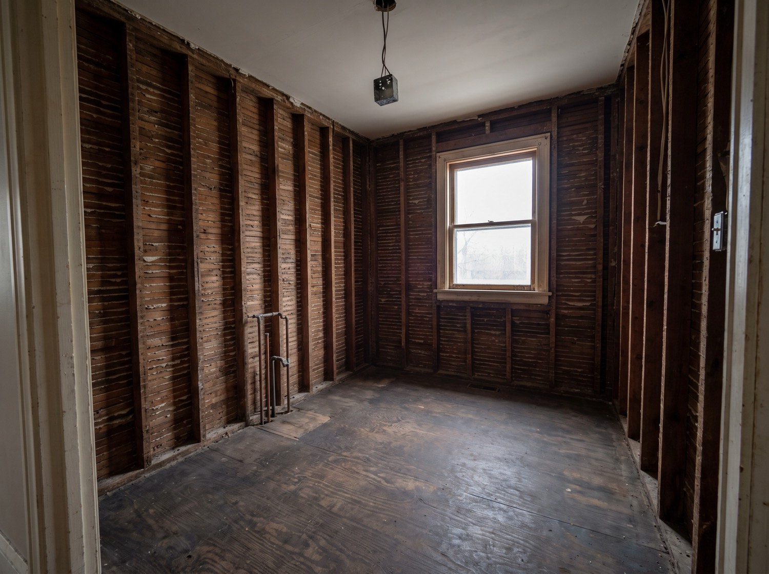 A gutted room stripped to the studs with the floor swept clean after debris removal