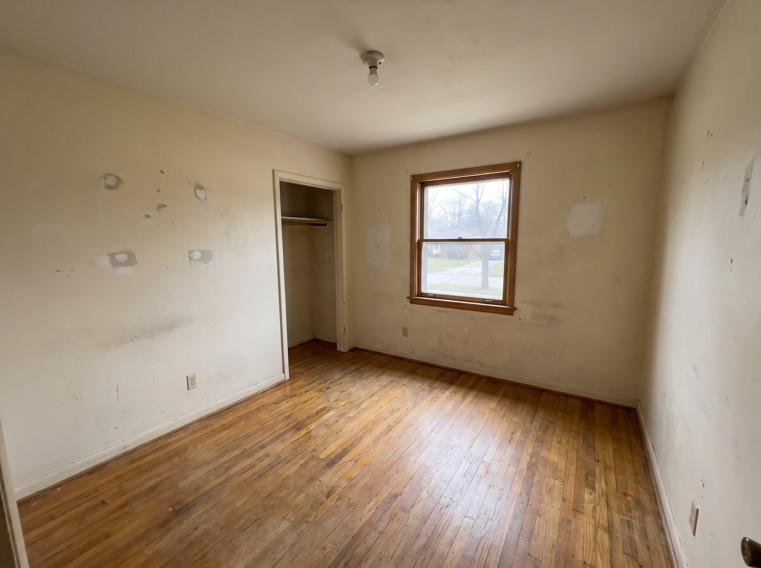 A cleared and swept room in an older home after a full cleanout, bare floor and daylight through the window