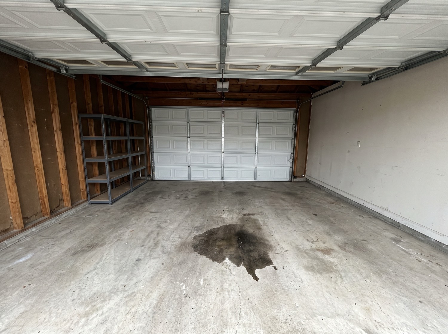 An emptied two-car garage after a cleanout, swept concrete floor and bare shelving